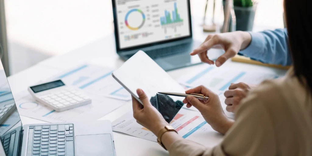 Asesoría contable y financiera en Colombia, dos profesionales revisando indicadores y gráficos en laptop y tablet